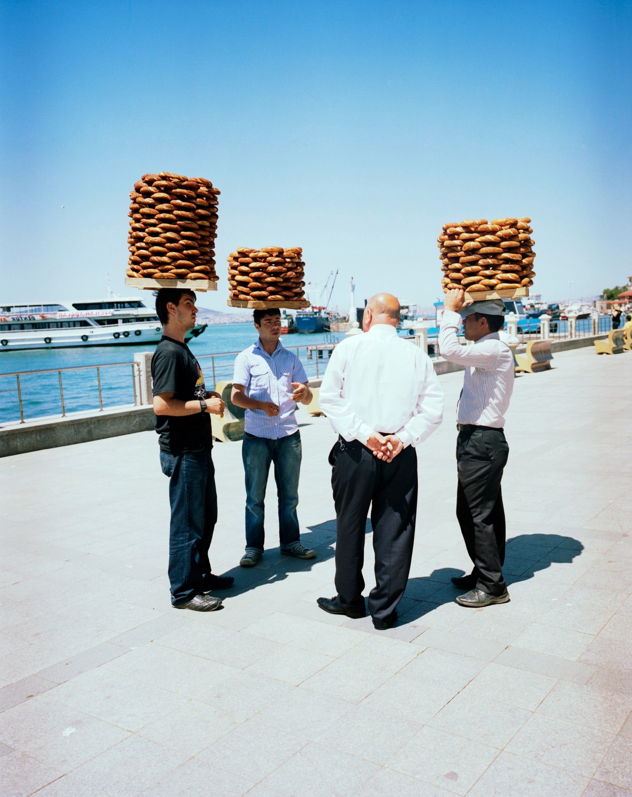 Semit sellers carrying stacked trays of Turkish bagels on their heads at Istanbul's waterfront.