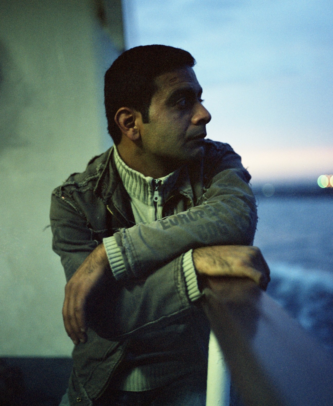 Man in jacket gazing at the Bosphorus during evening on the Kadıköy ferry.