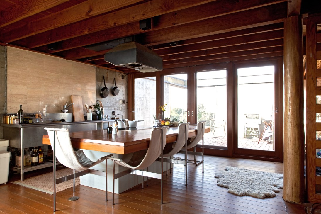 Kitchen-dining room with wooden ceiling beams, stainless steel sink, and dining table opening to terrace.