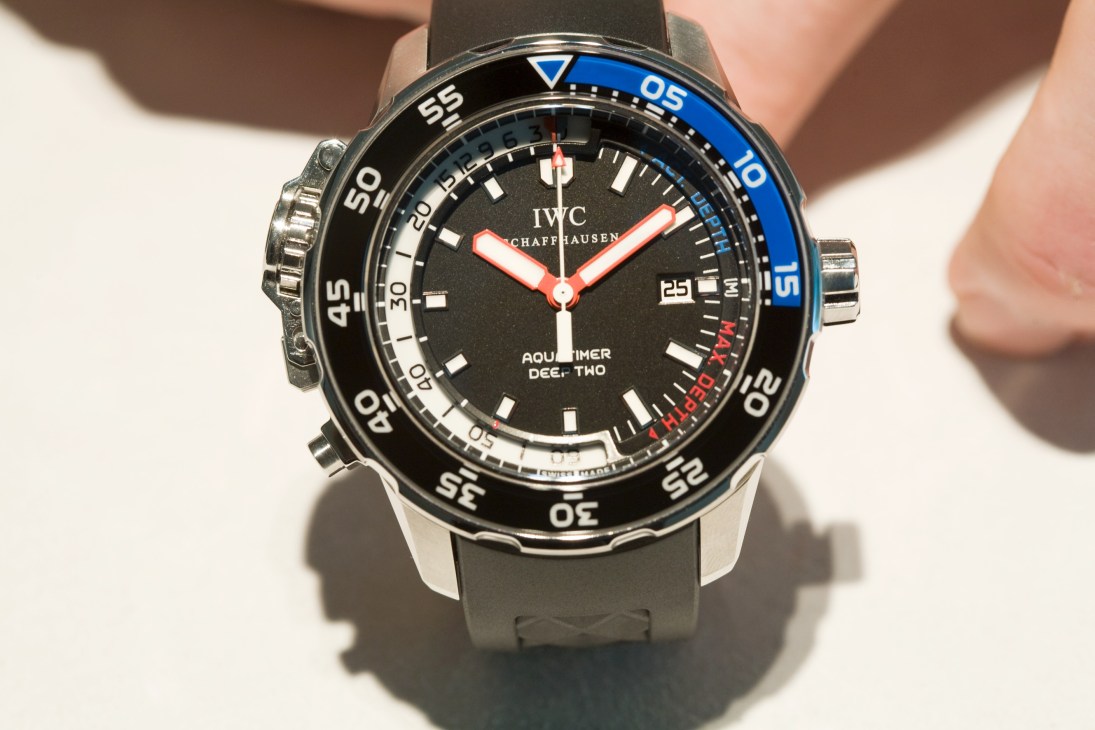 IWC Aquatimer dive watch with black dial, red hands, and blue bezel on rubber strap.