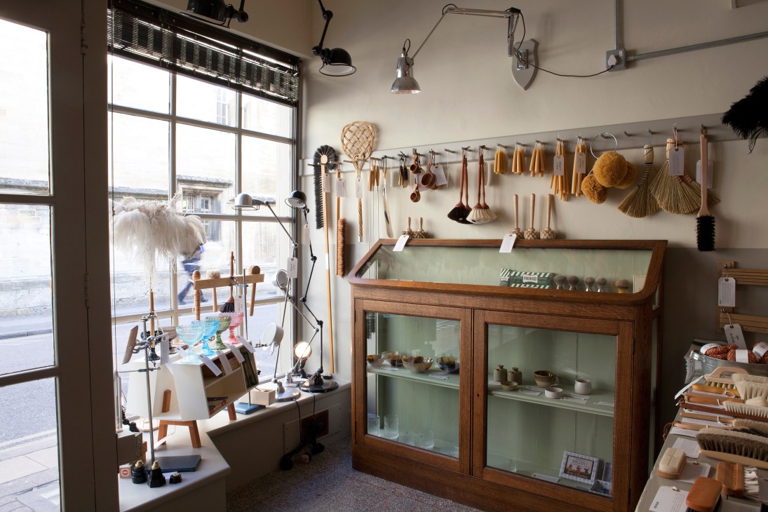 Interior of Objects of Use shop displaying kitchen tools and brushes hung on wall rails with wooden display cabinet.