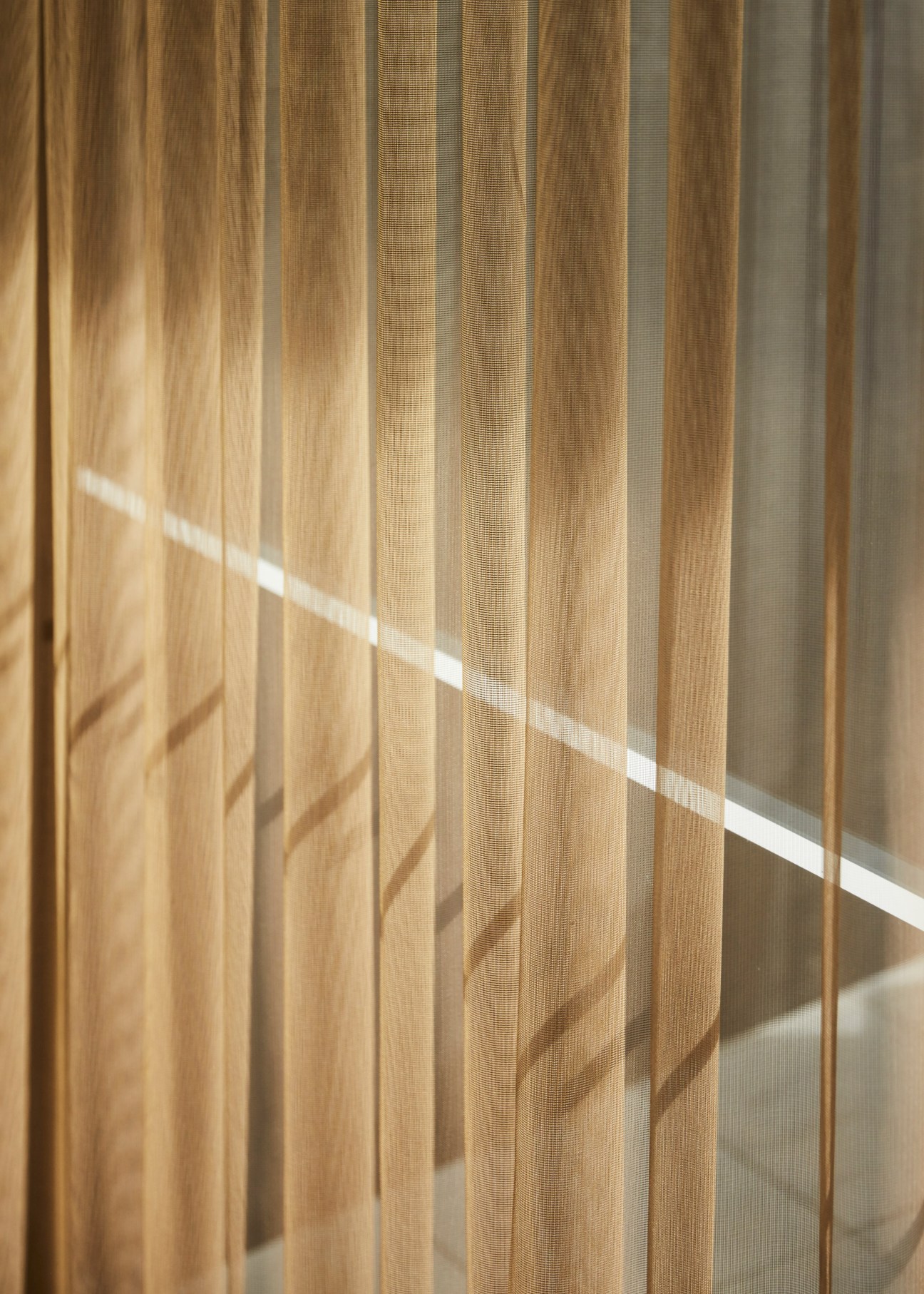 Sunlight streaming through sheer beige linen curtains in a Jackalope Hotel bedroom.