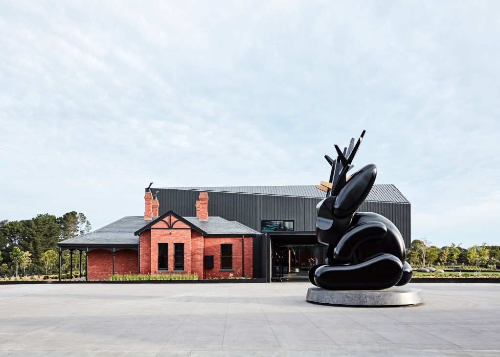 Hotel entrance with seven-metre black jackalope sculpture by Emily Floyd in foreground, red brick building and black metal structure behind