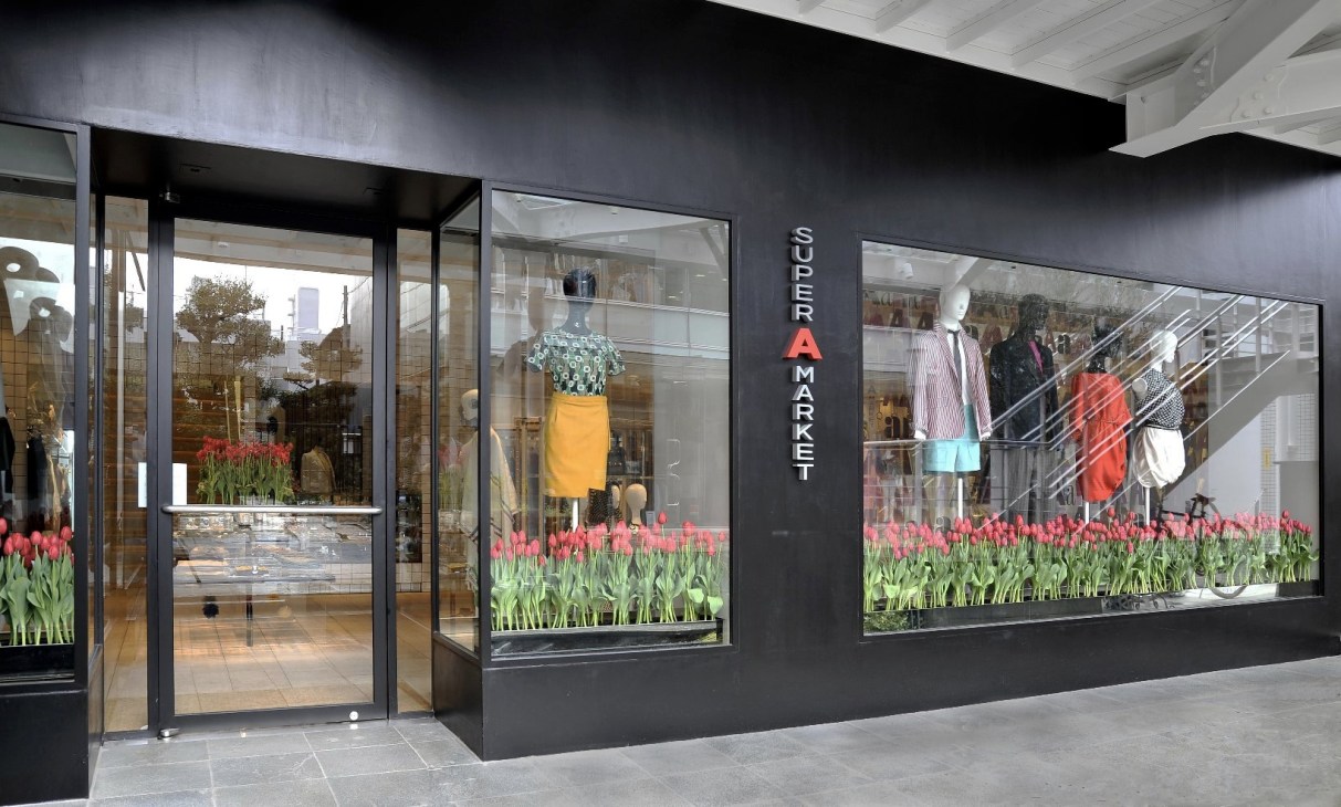 Super A Market storefront in Tokyo with black facade, large windows displaying clothing, and red tulips in window displays.