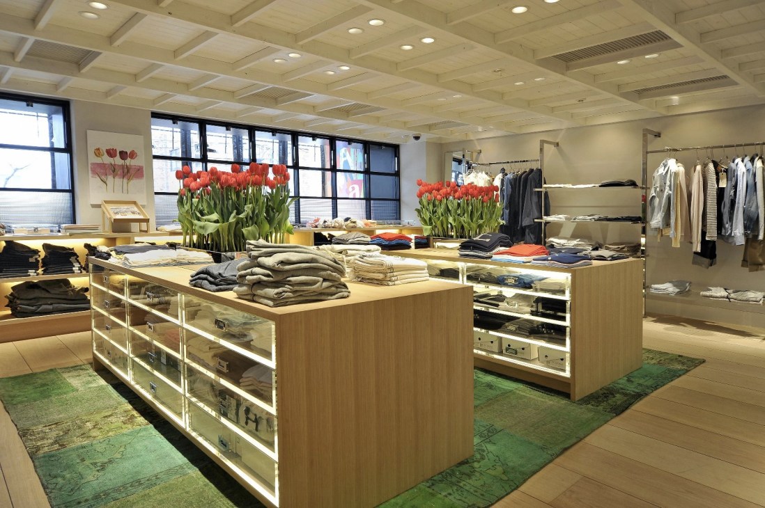 Interior of Super A Market concept store in Tokyo with wooden display tables, clothing racks, and red tulip flowers.