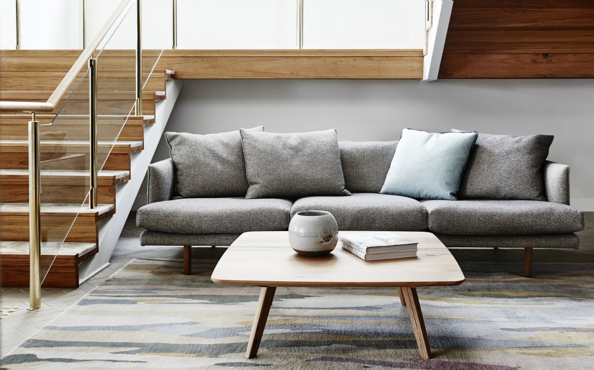 Contemporary living room displaying a grey upholstered sofa with wooden legs and a light wood coffee table.