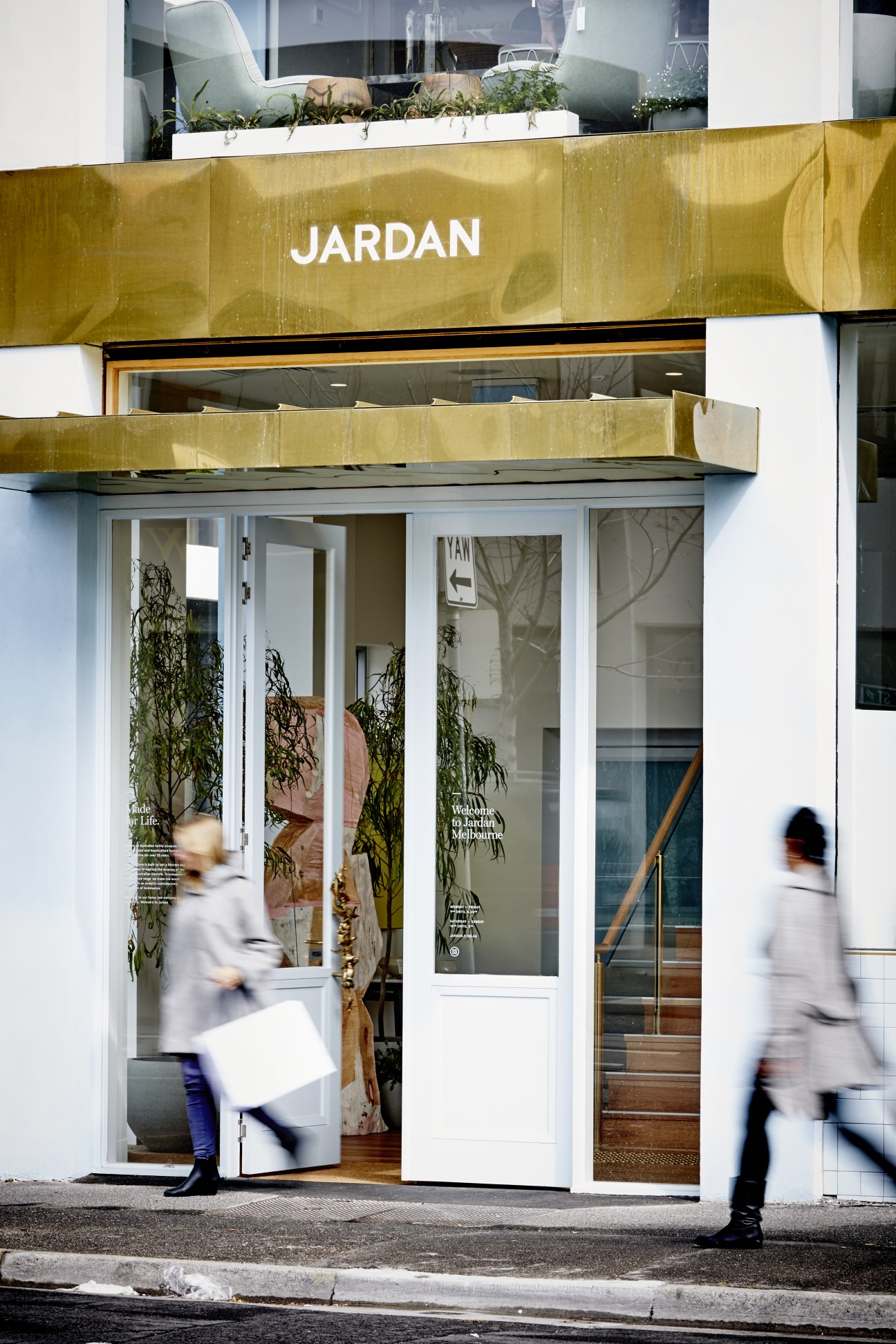 Jardan flagship store entrance with gold signage, white frame, and potted plants in Melbourne.