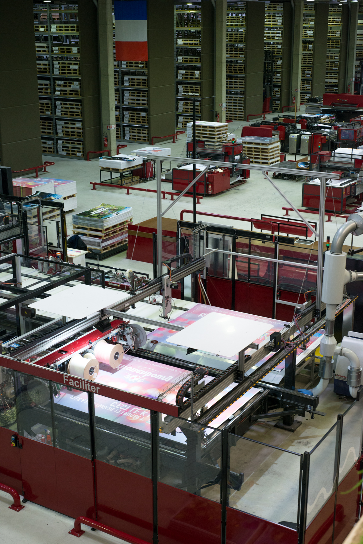 Industrial printing facility with red machinery producing advertising posters at JCDecaux headquarters.