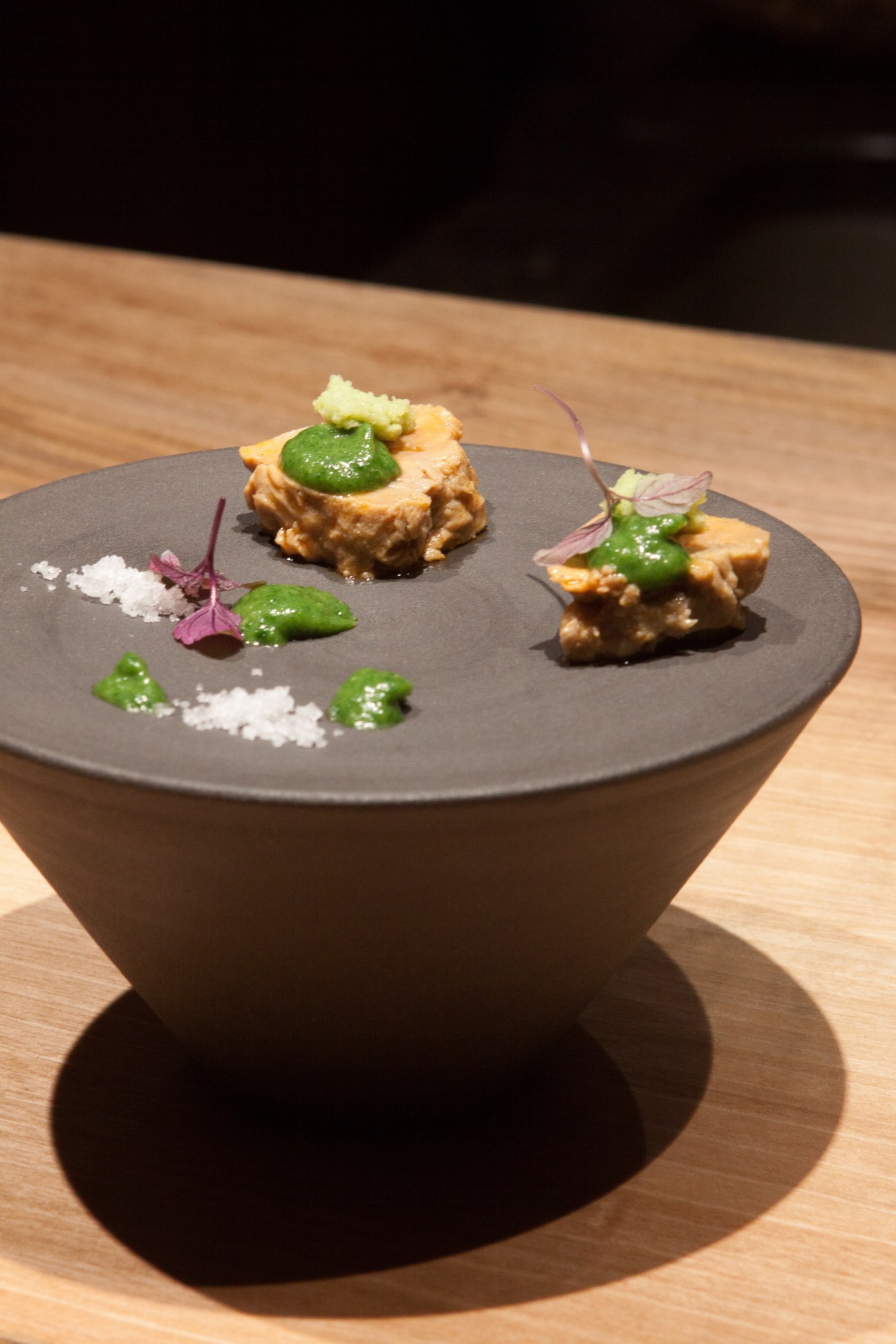 Plated Japanese cuisine at Jin restaurant featuring seared fish with wasabi and microgreens on dark plate.