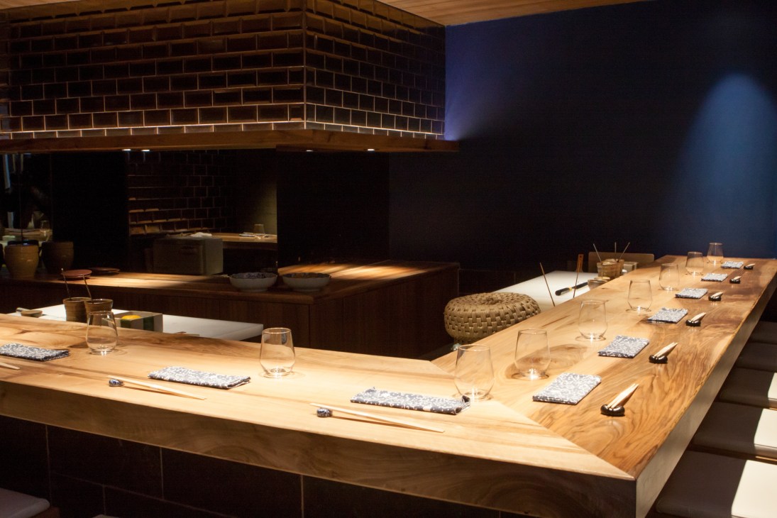 Japanese sushi counter at Jin restaurant in Paris with wooden seating and brick kitchen.
