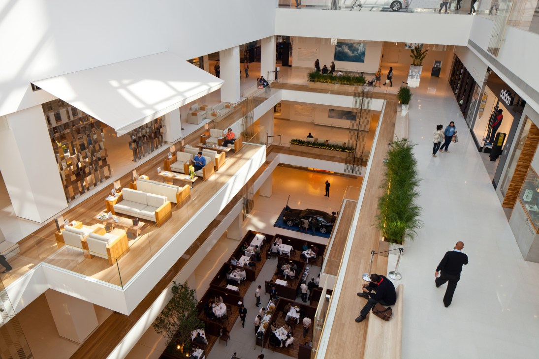 Aerial view of JK Iguatemi mall's multi-level atrium with communal spaces, seating areas, restaurants, and shoppers.