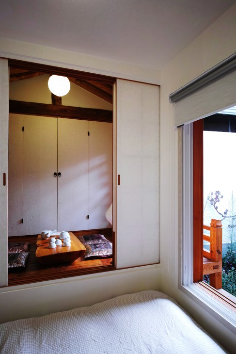 Modern bedroom in restored hanok with built-in wooden alcove, sliding doors and courtyard view.