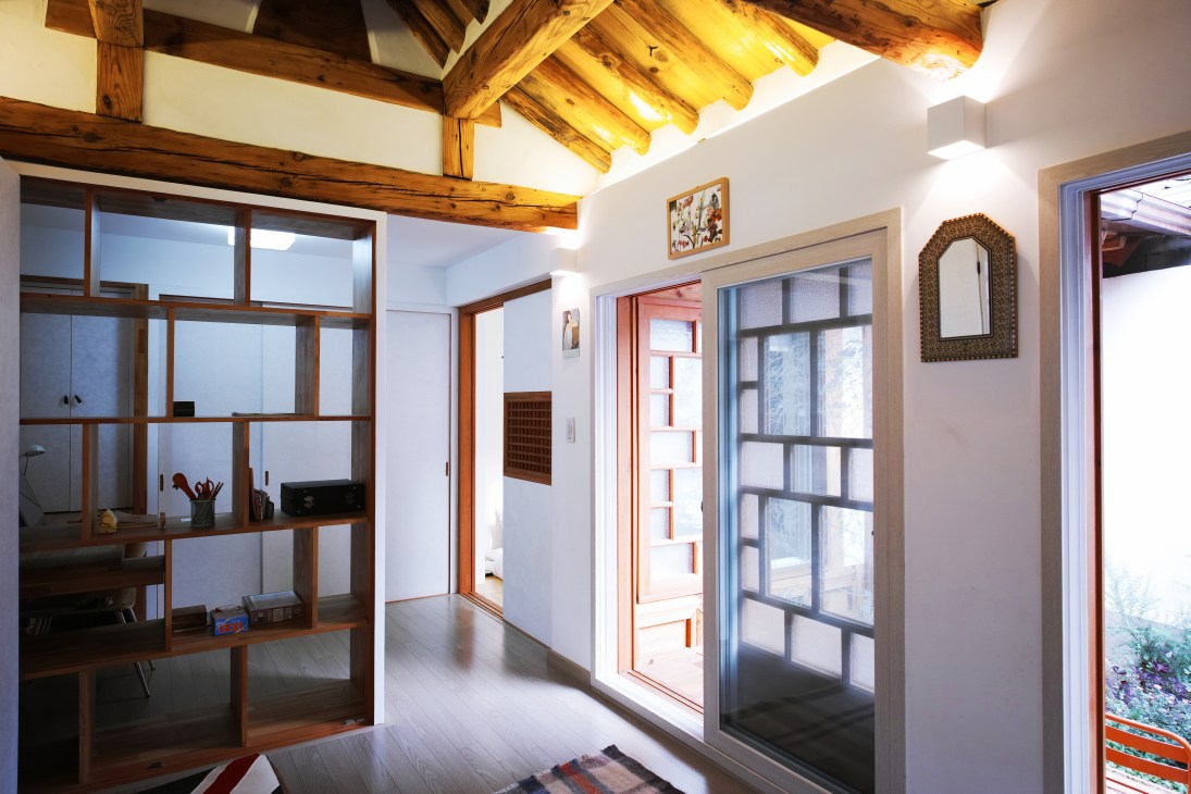 Modern living space in restored hanok with wooden beams, white walls, and traditional Korean architectural elements.