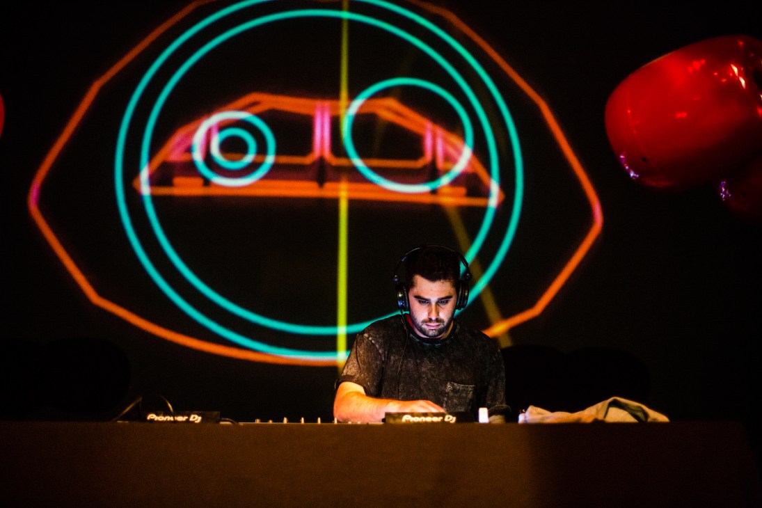 DJ performing at turntables against a colorful neon backdrop at ChaChá nightclub.