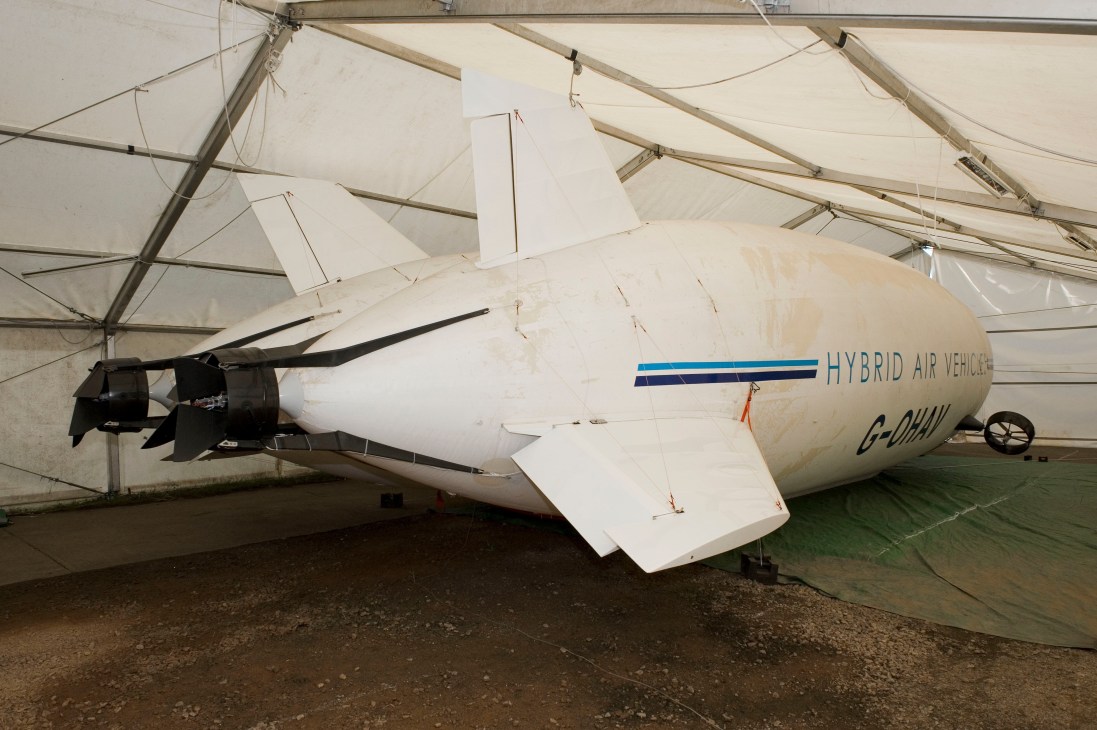 Hybrid Air Vehicles' demonstrator airship with wing-shaped gas bag parked inside a large hangar.