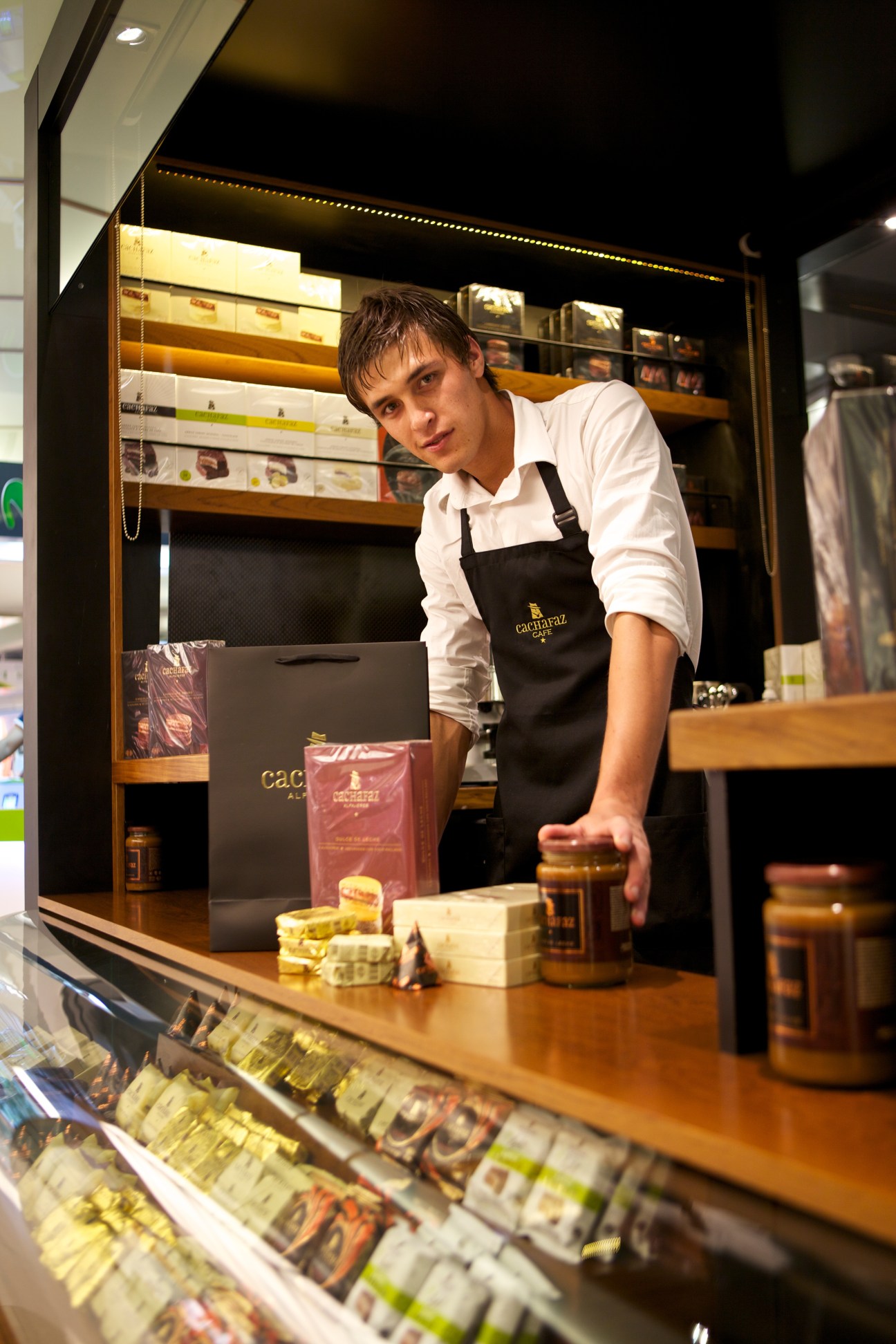 Cachafaz staff member at retail counter displaying alfajores and branded packaging