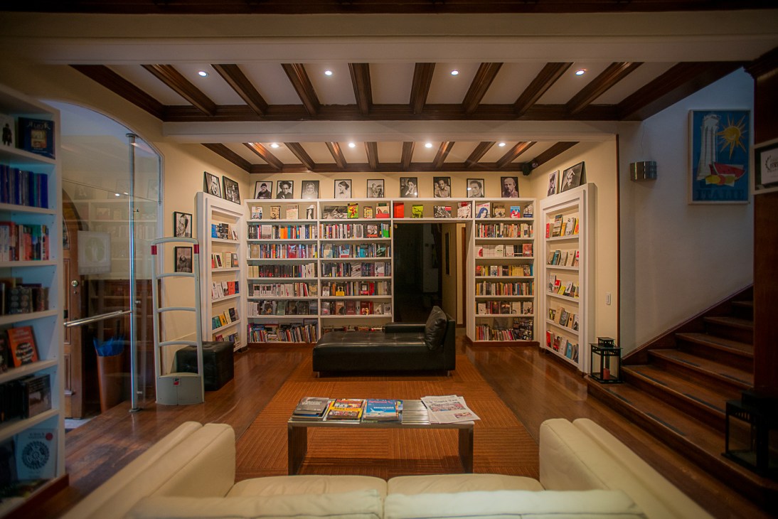La Madriguera del Conejo bookshop interior with floor-to-ceiling shelves, portraits, dark furniture and wooden ceiling beams.