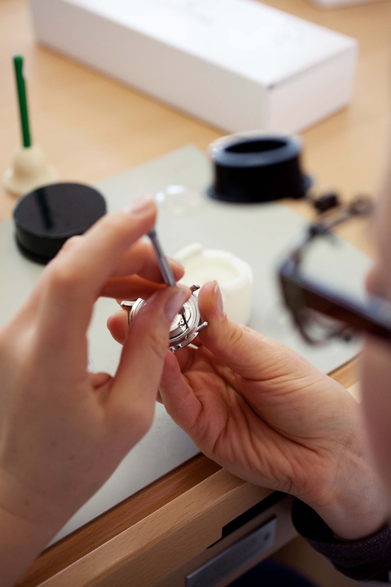 A person's hands holding a silver Junghans watch mechanism during assembly or inspection.