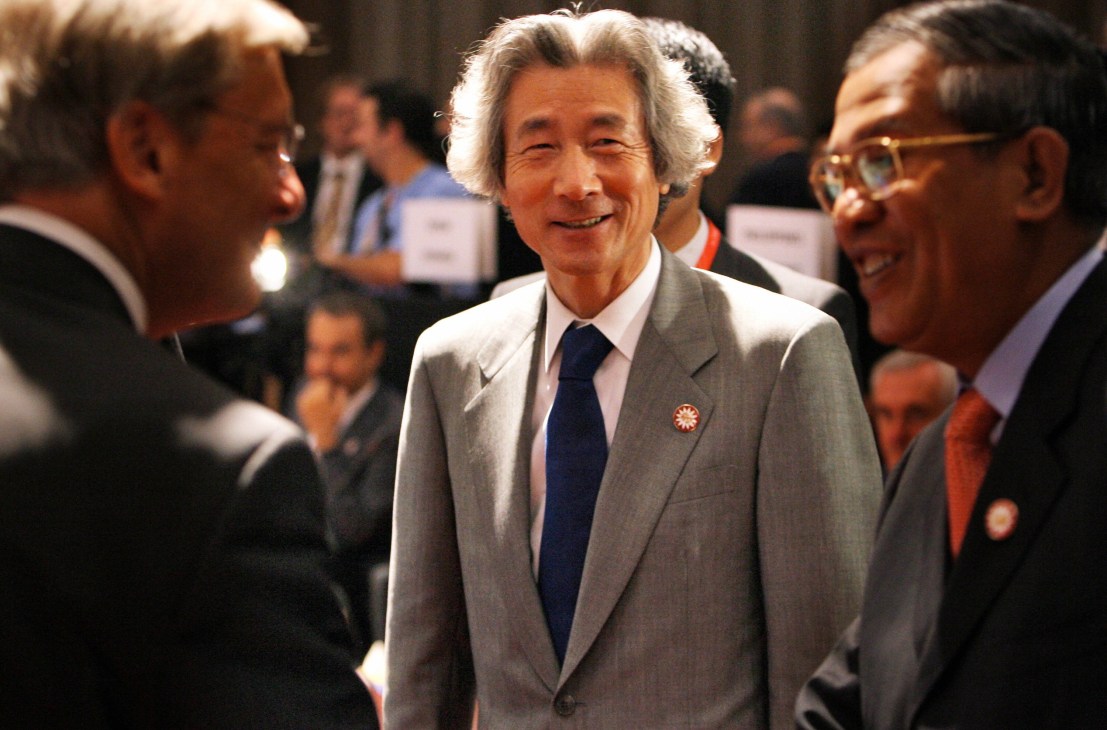 Junichiro Koizumi in a grey suit and dark tie at a formal event, surrounded by other officials.