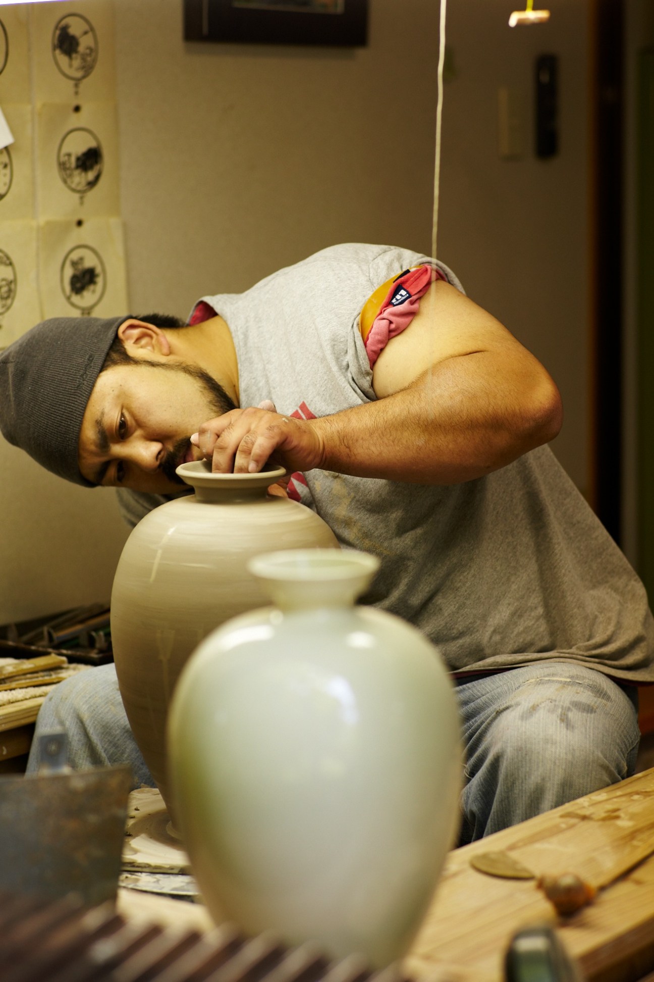 Potter working at a pottery wheel, shaping a cream-colored ceramic vessel at Chin Jukan kiln.