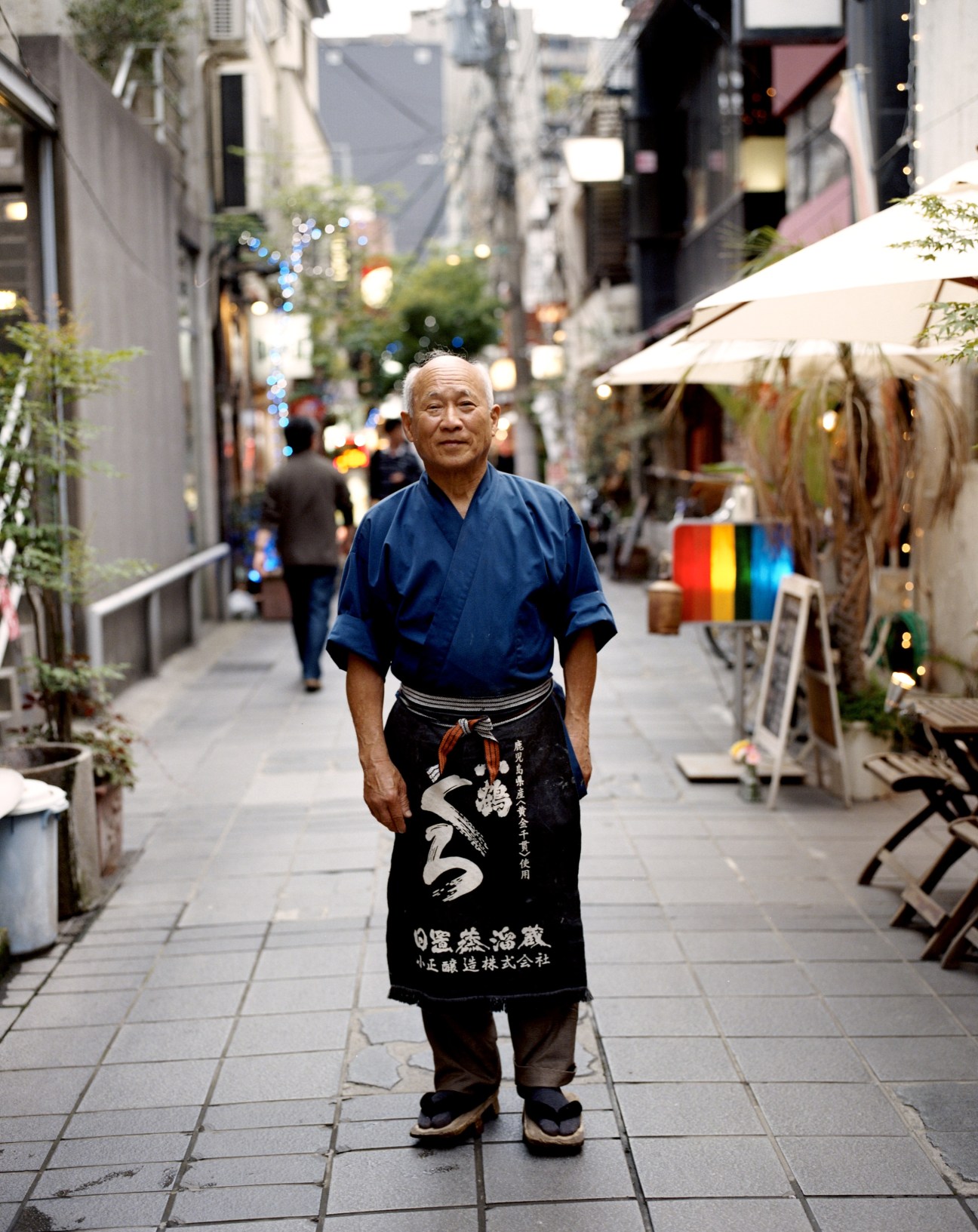 Mitsuhiro Kubo, master of Gonbei restaurant, stands in a narrow alley wearing traditional Japanese clothing.