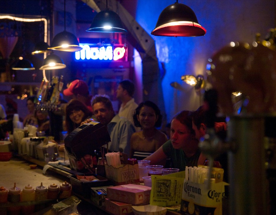 Patrons enjoying drinks at Grinders bar in Kansas City's Crossroads district under colorful pendant lighting.