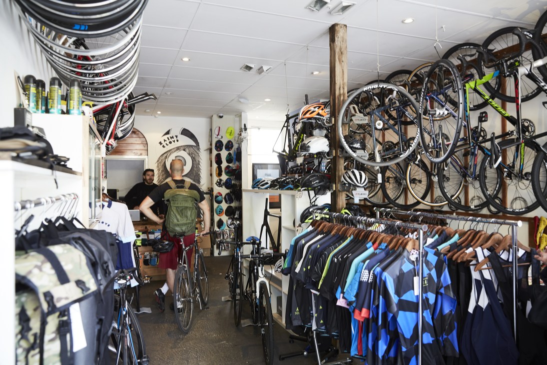Interior of Saint Cloud bike and clothing shop displaying bicycles, helmets, and cycling apparel with staff assistance.