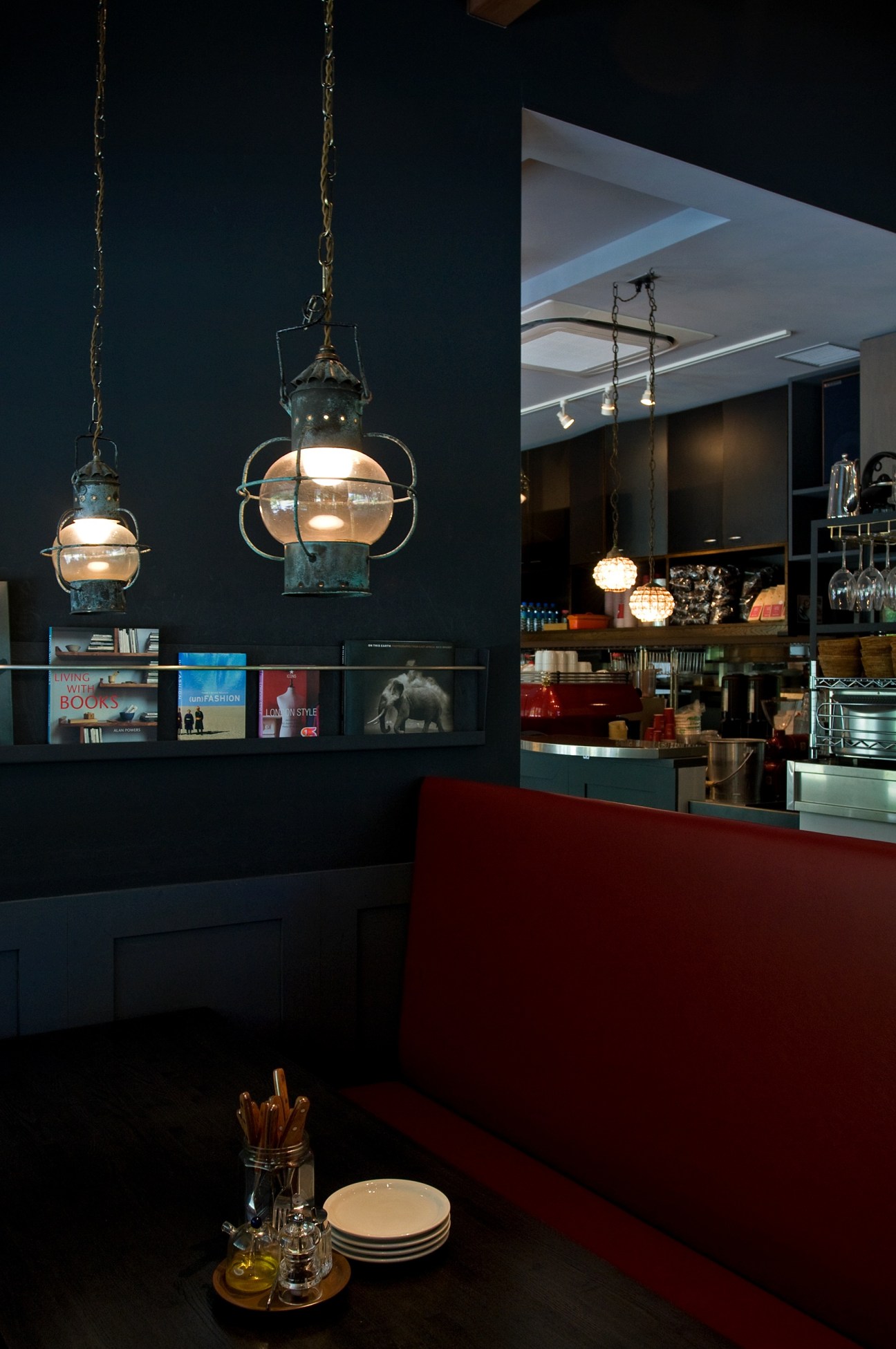Modern restaurant interior with hanging pendant lamps, dark walls, and red seating in Karuizawa, Tokyo.