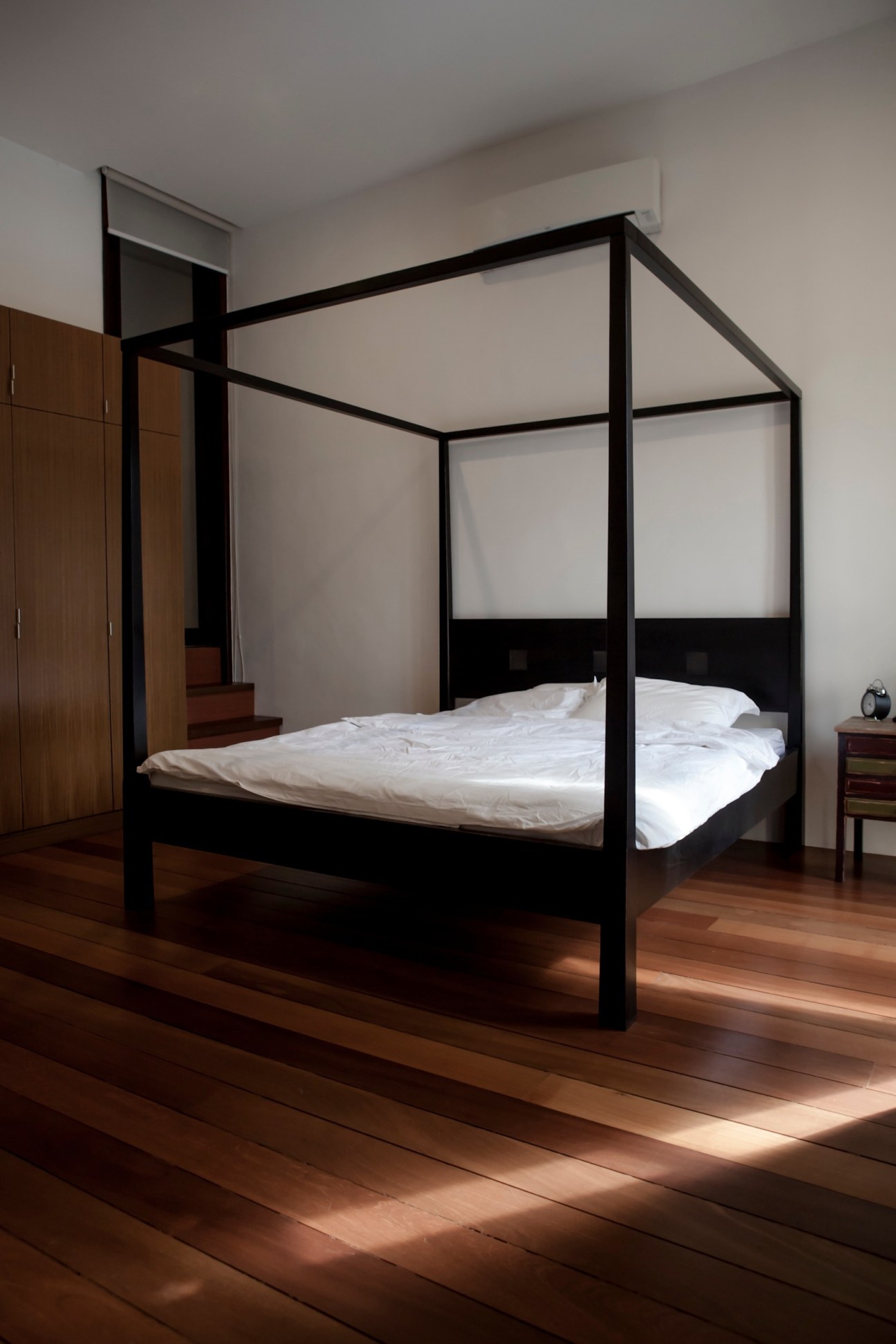 Modern minimalist bedroom with black four-poster bed and white bedding in Tan Ngiap Heng's house.