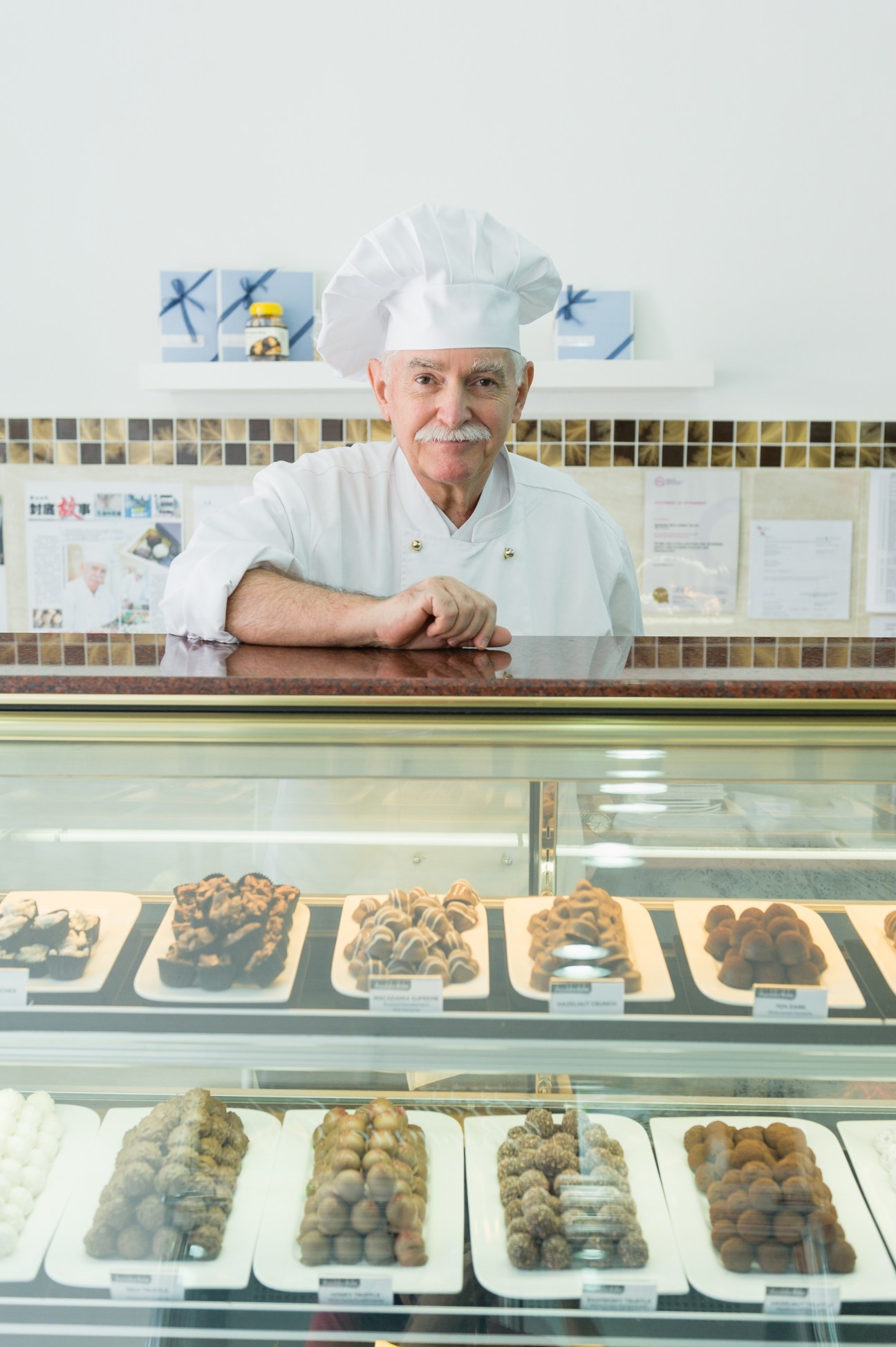 Swiss chocolatier Reto Marzari stands behind a display counter of truffles and pralines at Chocolate Atelier.