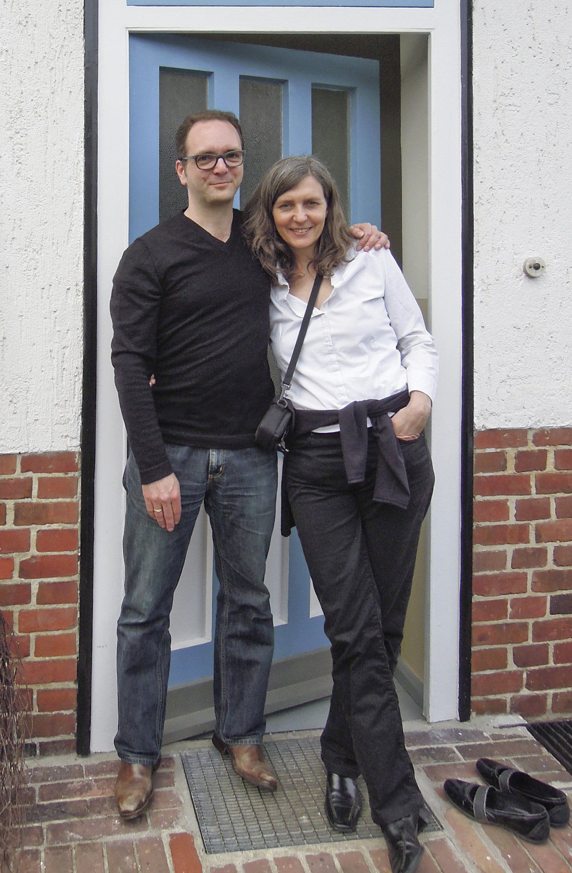 Ben Buschfeld and his wife Katrin stand together at the entrance of Tautes Heim guesthouse in Berlin.