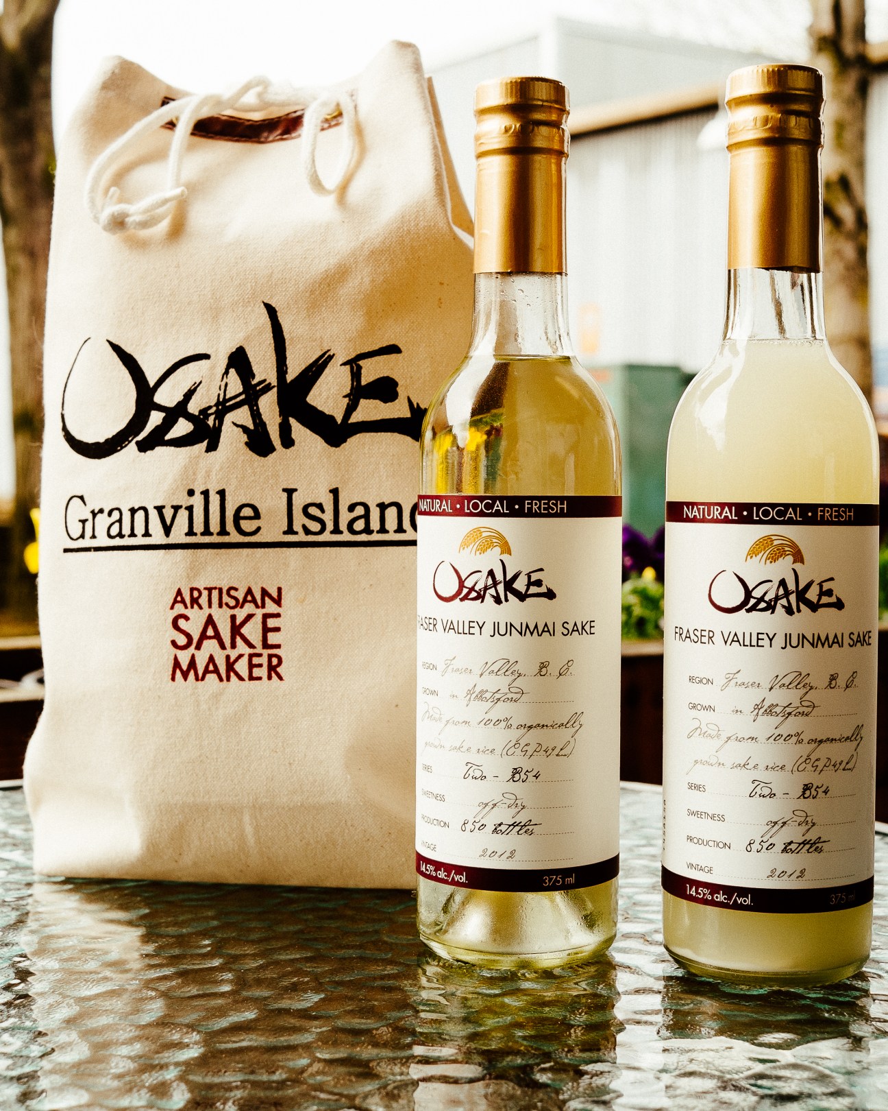 Two bottles of Osake Fraser Valley Junmai sake next to a canvas Granville Island tote bag from Artisan Sake Maker.