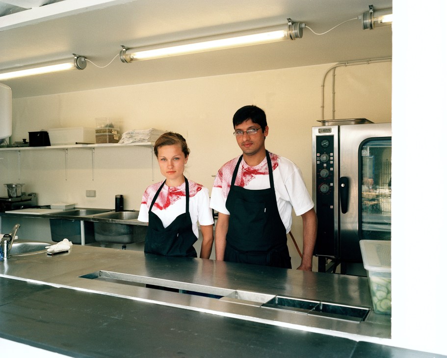 Two baristas stand behind a counter in a bright, minimalist kitchen at Karriere café in Copenhagen.