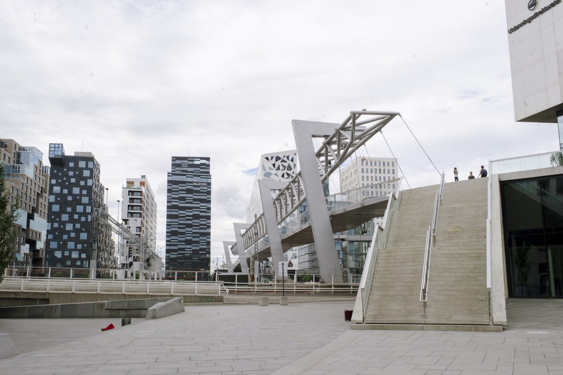Modern waterfront district with distinctive striped and patterned high-rise buildings along a paved plaza with architectural structures.