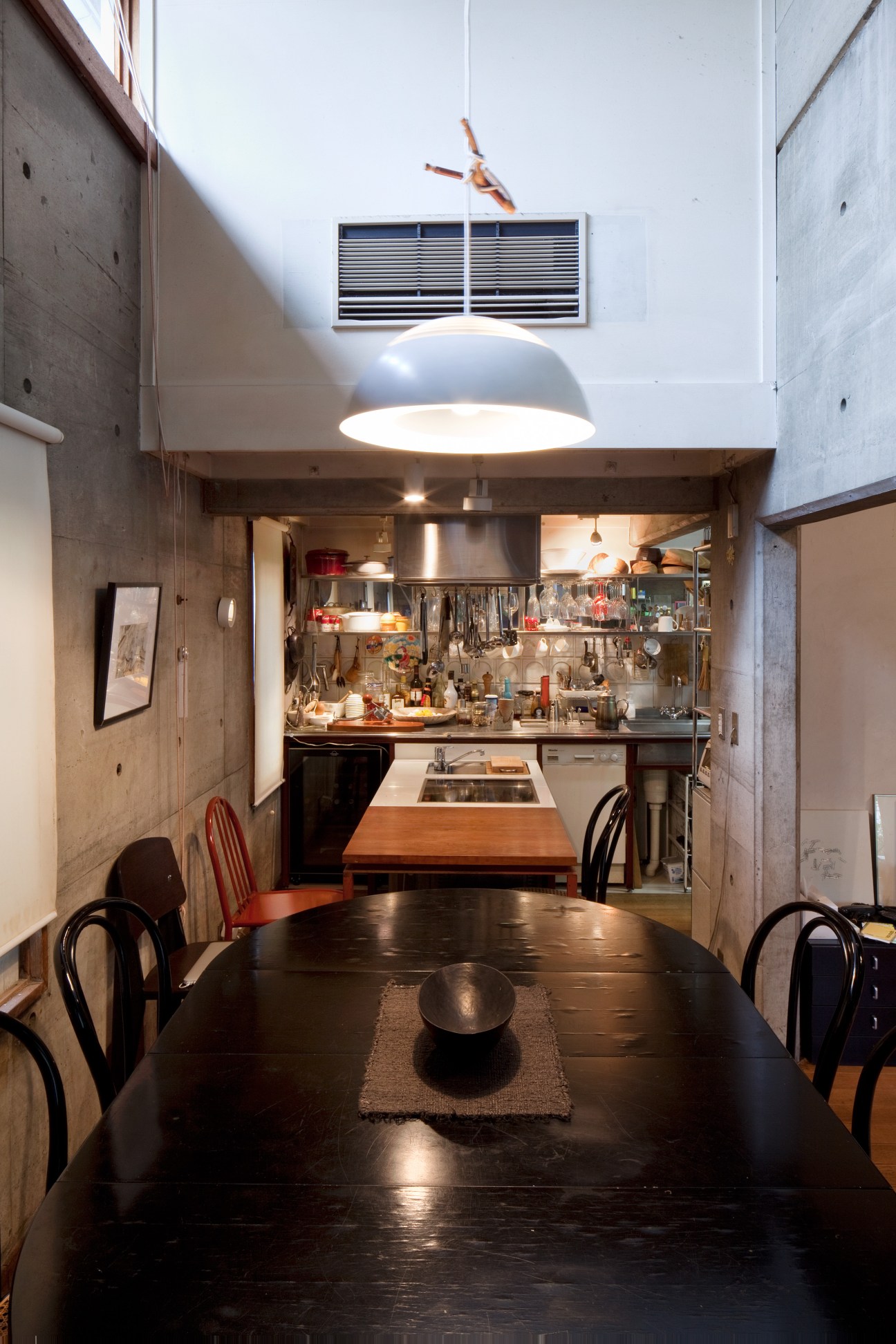 Modern dining area with dark wooden table, black chairs, and compact kitchen with stainless steel appliances