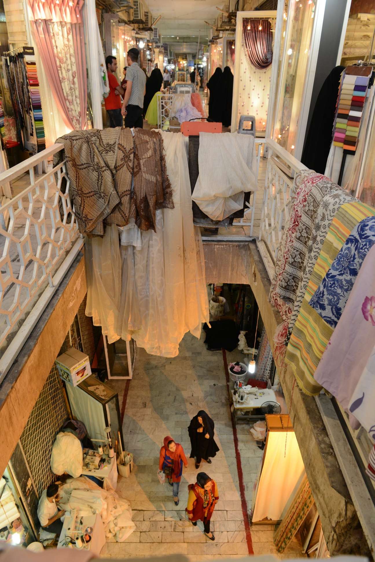 Overhead view of people shopping in a curtain fabric market with colorful fabrics displayed on racks.