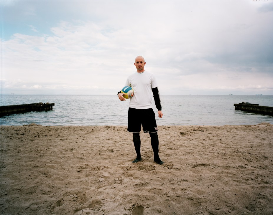 Volleyball player Lasse Helverskov holding a ball on a sandy beach in Klampenborg, Copenhagen