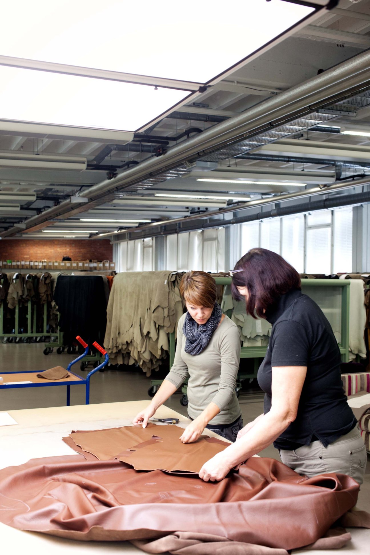 Two workers inspect leather material at a Walter Knoll production facility.