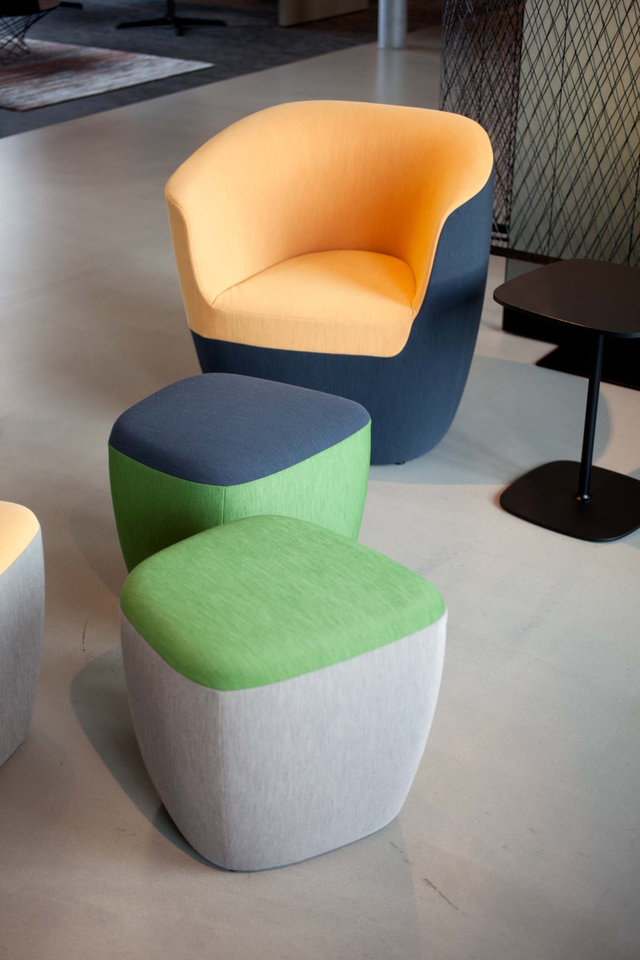 Modern upholstered furniture pieces including a yellow armchair and green pouf on display in Walter Knoll showroom.
