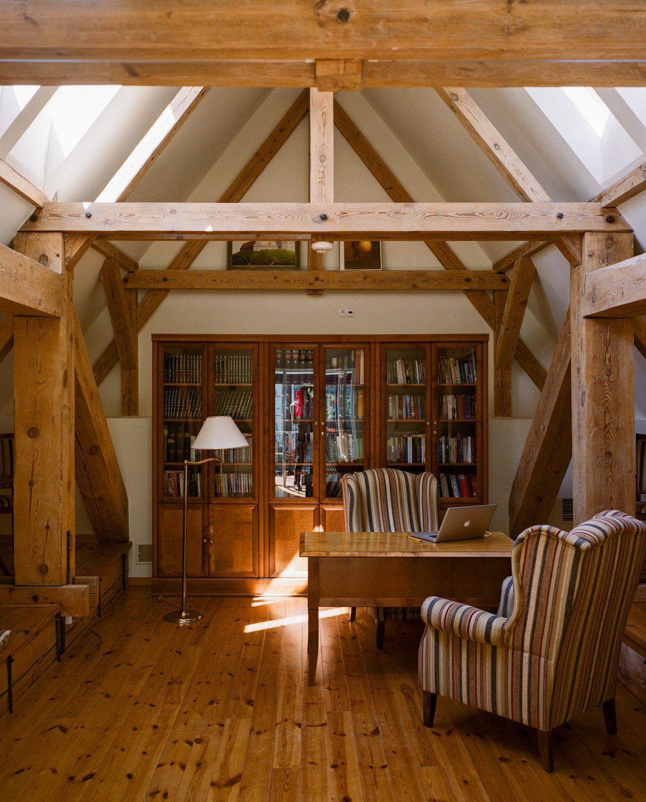Library with original wooden beams, desk, bookshelves, and skylights at Nibork retreat.