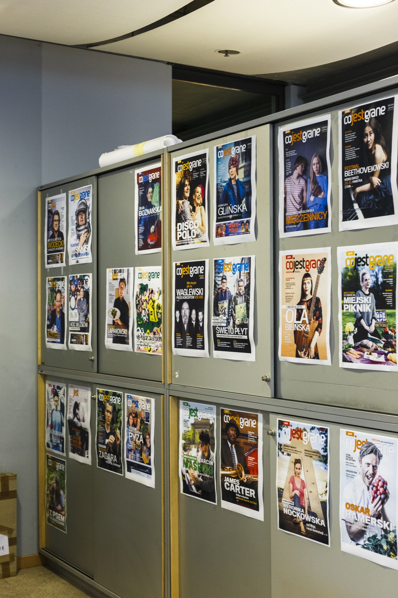 Display of magazine covers for 'What's Playing?', Gazeta Wyborcza's culture supplement, mounted on a light green wall.