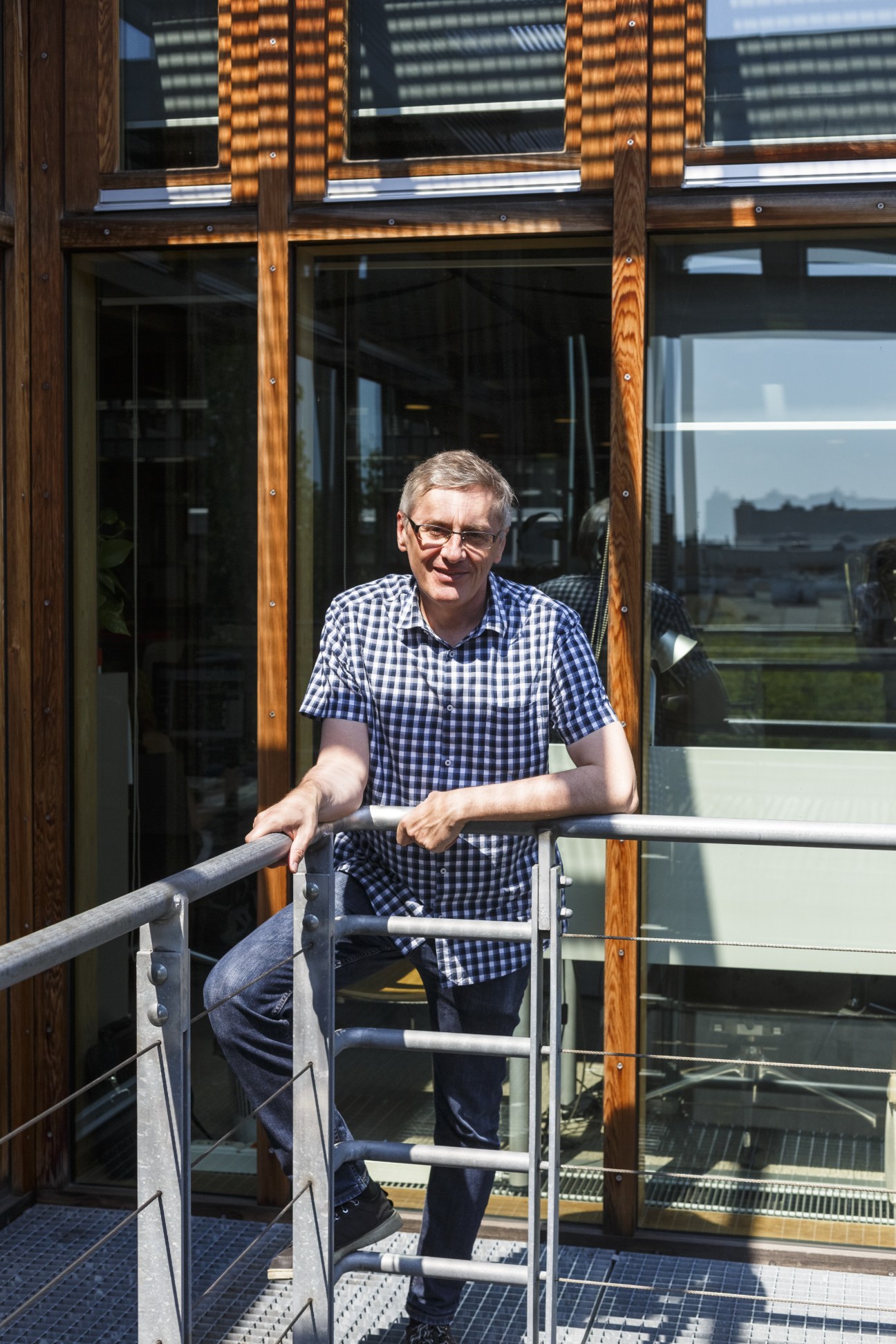Dariusz Bartoszewicz, writer for the Warsaw supplement, standing on a terrace with wooden frames and metal railings.