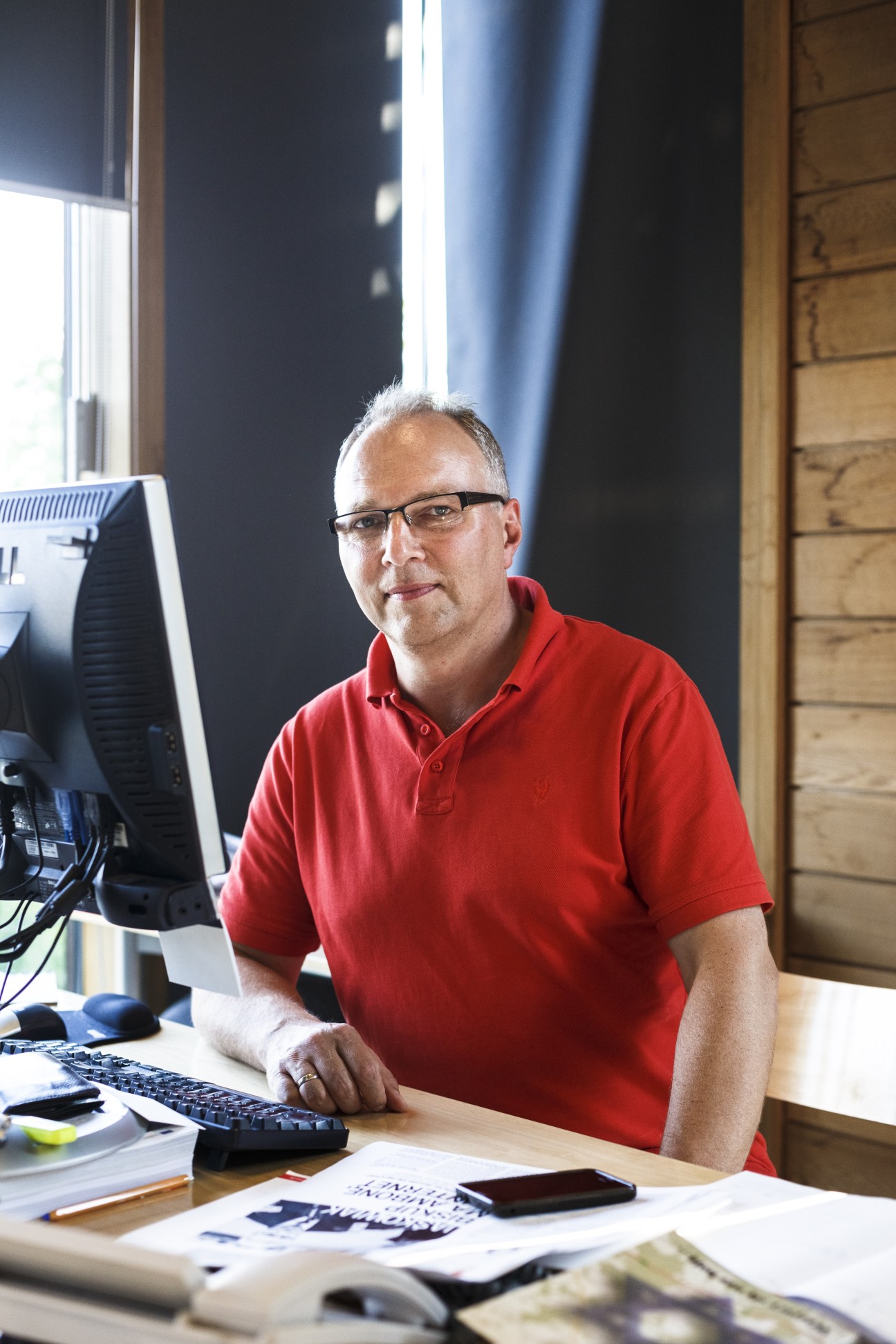 Jarosław Kurski, deputy editor in chief of Gazeta Wyborcza, sitting at his desk in a red shirt.