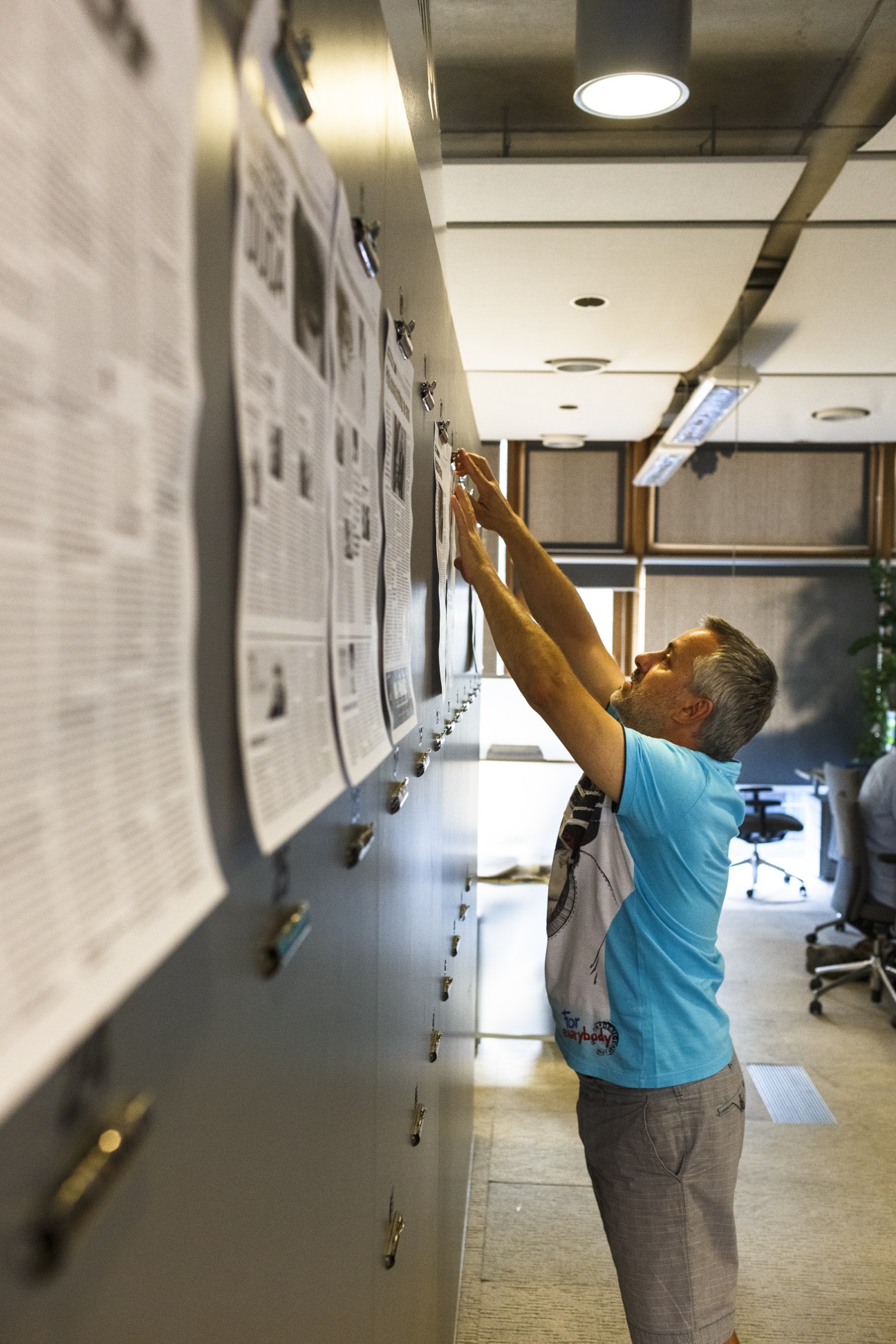 A journalist posts newspaper pages on a wall in the Gazeta Wyborcza office.
