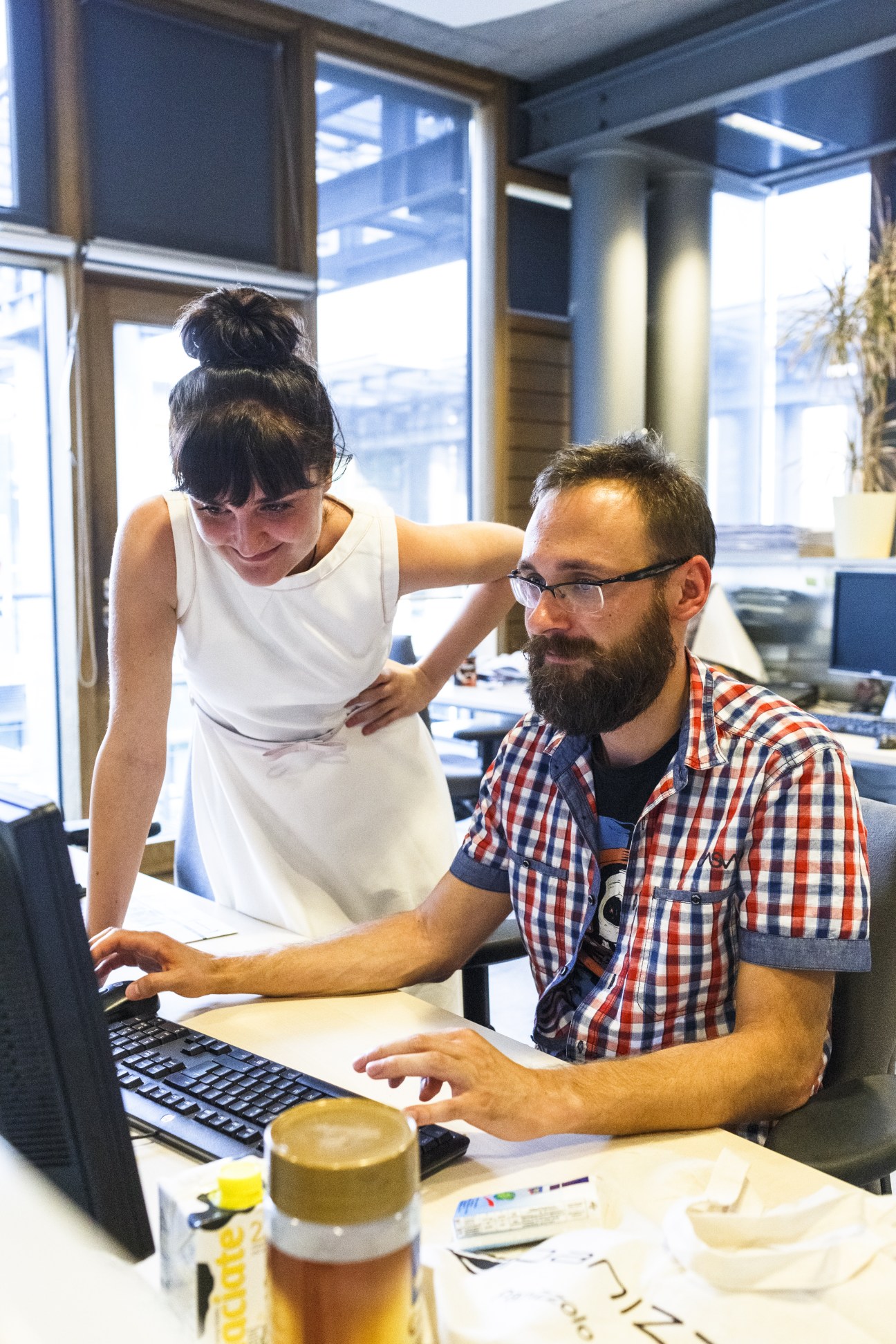 Two journalists collaborate at a desk with a computer in Gazeta Wyborcza's bright editorial office.