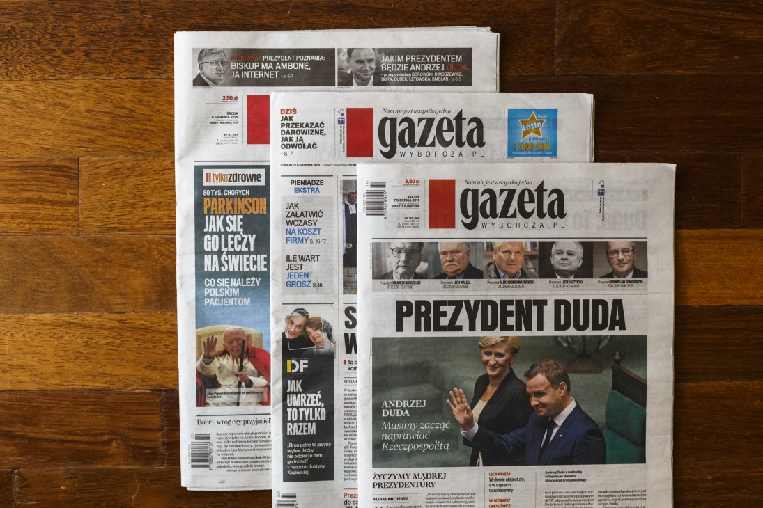Multiple copies of Gazeta Wyborcza newspaper displayed on a wooden surface showing front pages with Polish headlines and presidential coverage.