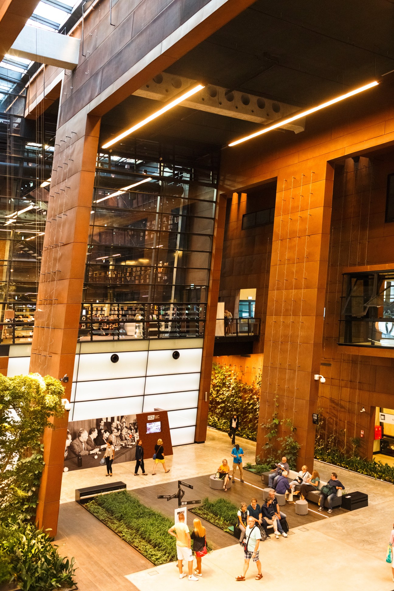 Interior atrium of the European Solidarity Centre with orange-tiled walls, skylights, and visitors walking through the modern space.