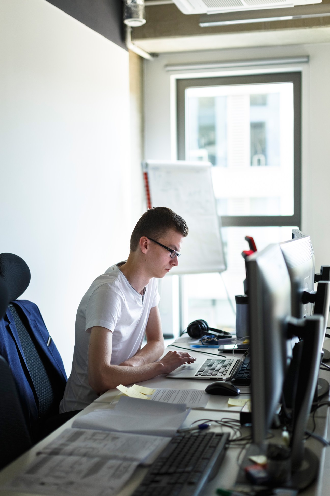 Young man wearing glasses working at a computer desk in a bright office space at CTAdventure.