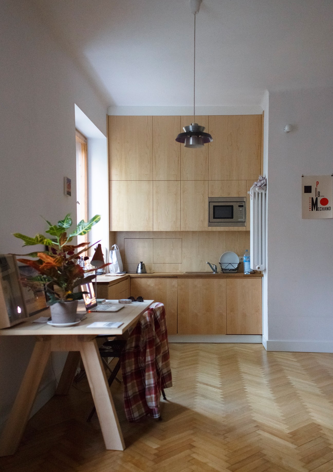 Modern kitchen and dining area in Adam Przywara's studio flat with wooden cabinetry and parquet flooring.