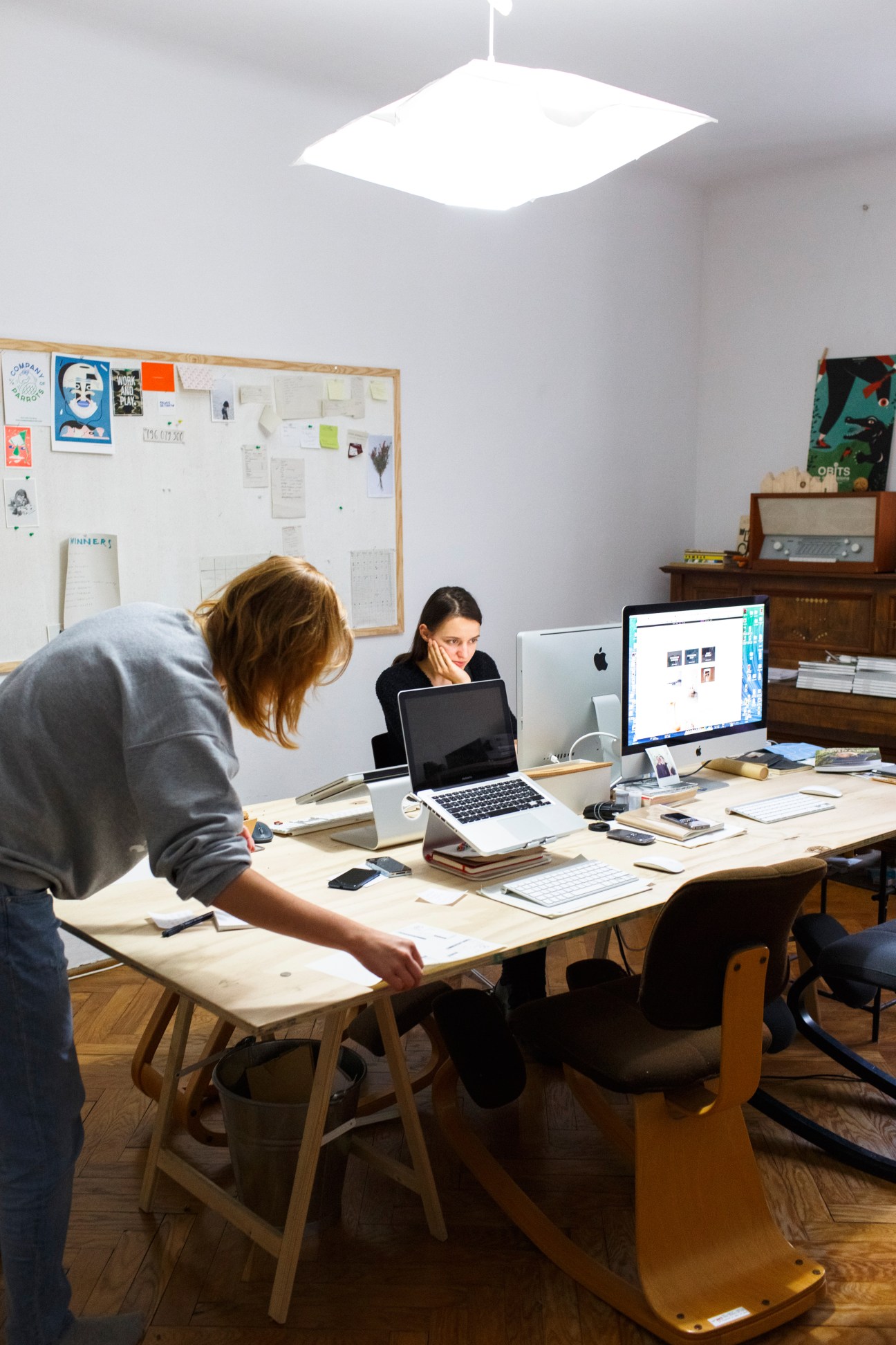 Two interns working at a desk with laptops and design materials in a minimalist Warsaw office.